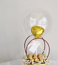 16 ferrero rocher chocolates in a round handle basket with a clear transparent balloon stuffed with a golden balloon