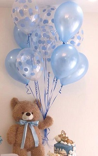 A 12 inches Teddy clutching 10 Blue and polka dotted blue balloons on sticks