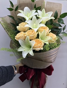 4 White Lilies with 6 peach roses in a bouquet wrapped in brown