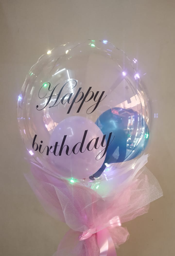 Bouquet of clear printed happy birthday transparent balloon with pink blue balloons in the balloon wrapped in pink and jute bow led lights